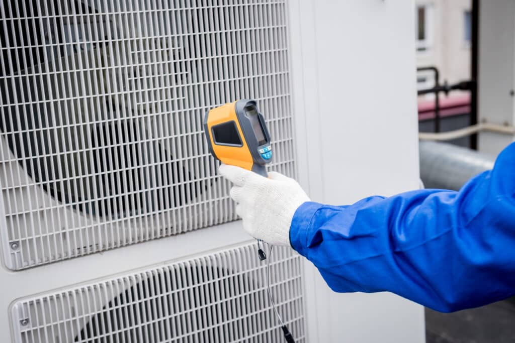 Technician uses a thermal imaging infrared thermometer to check the condensing unit heat exchanger