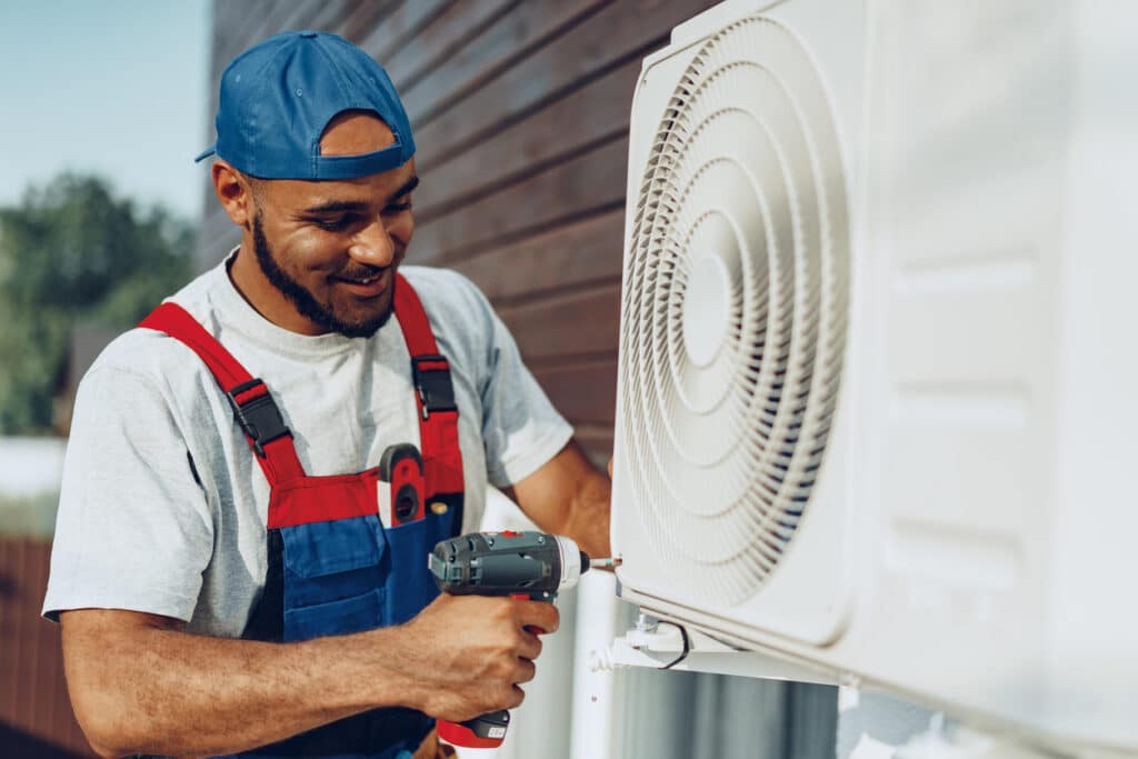 Repairman in uniform installing the outside unit of air conditioner